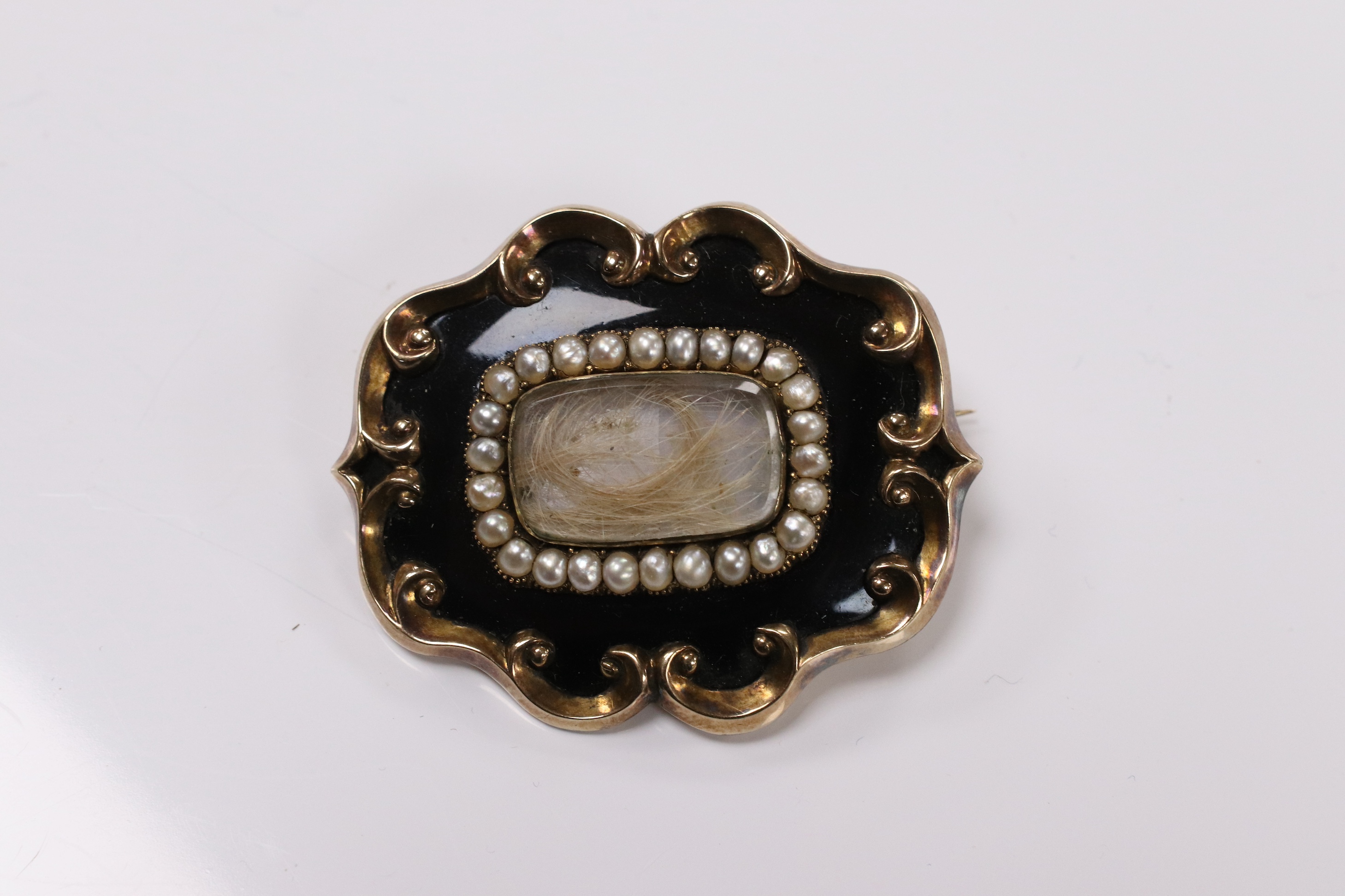A late Victorian yellow metal, black enamel and split pearl set mourning brooch, with engraved inscription 'Sarah Appleyard, born 16th December 1804, died 12th Jan 1886', 46mm, with hair below a glazed panel. Condition -